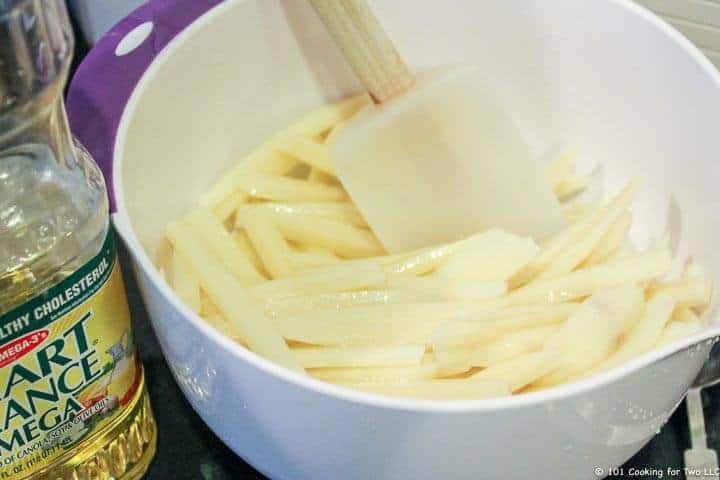 Mezclar las patatas fritas con el aceite en un bol blanco