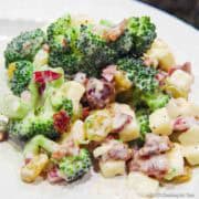broccoli salad with bacon and raisins on a white plate.