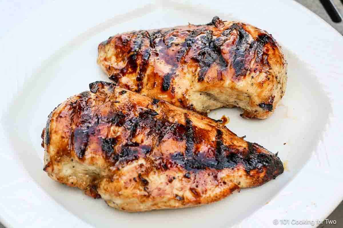 grilled glazed chicken breasts on a white plate.