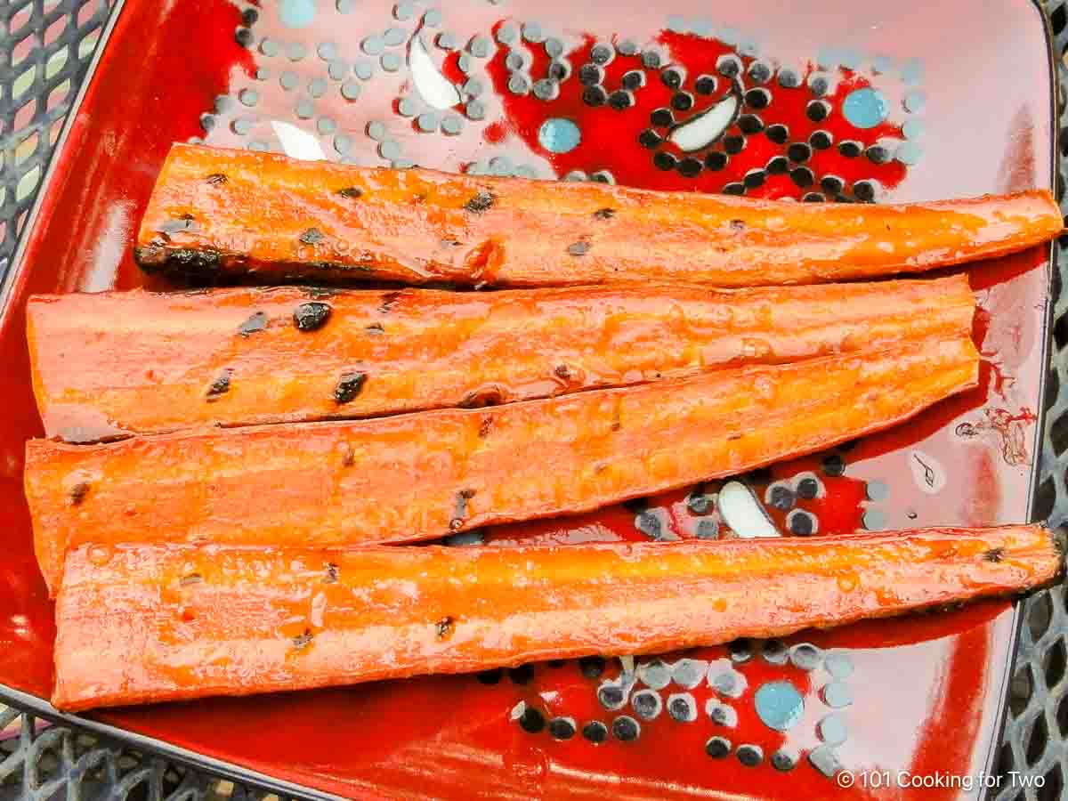 grilled honey glazed carrots on a red plate.