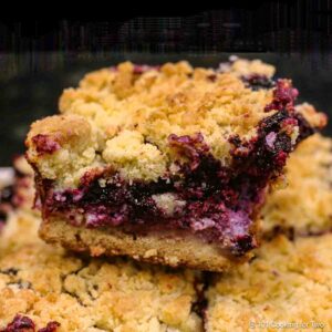 A pile of blueberry cream cheese bars with crumble topping.