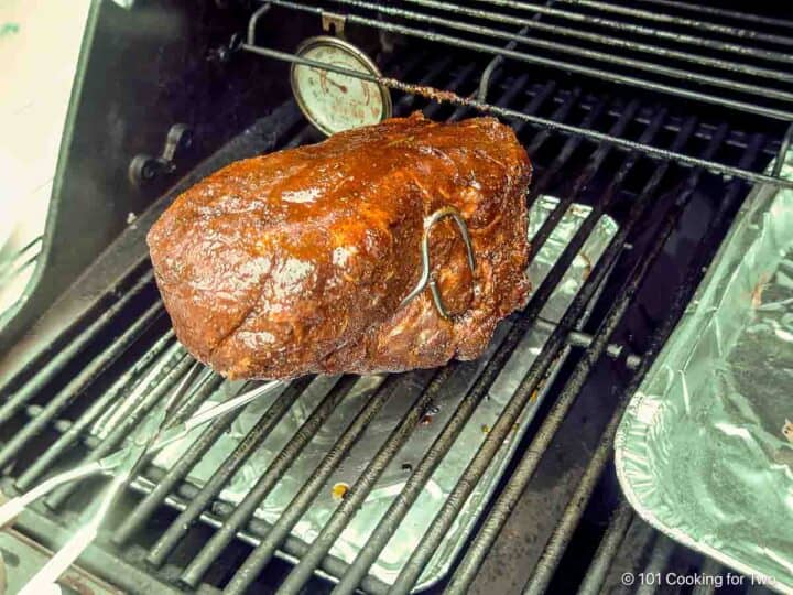 placing rubbed pork butt on the indirect side of the grill.