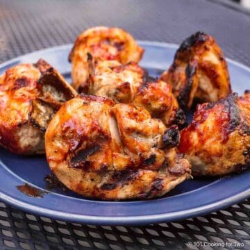 BBQ split bone-in chicken breasts on a plate.