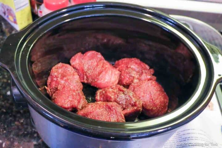 Raw pork tenderloin with dry rub in a crockpot.