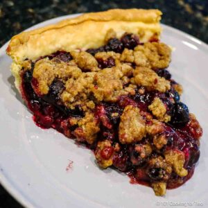 blueberry crumble pie on a gray plate.