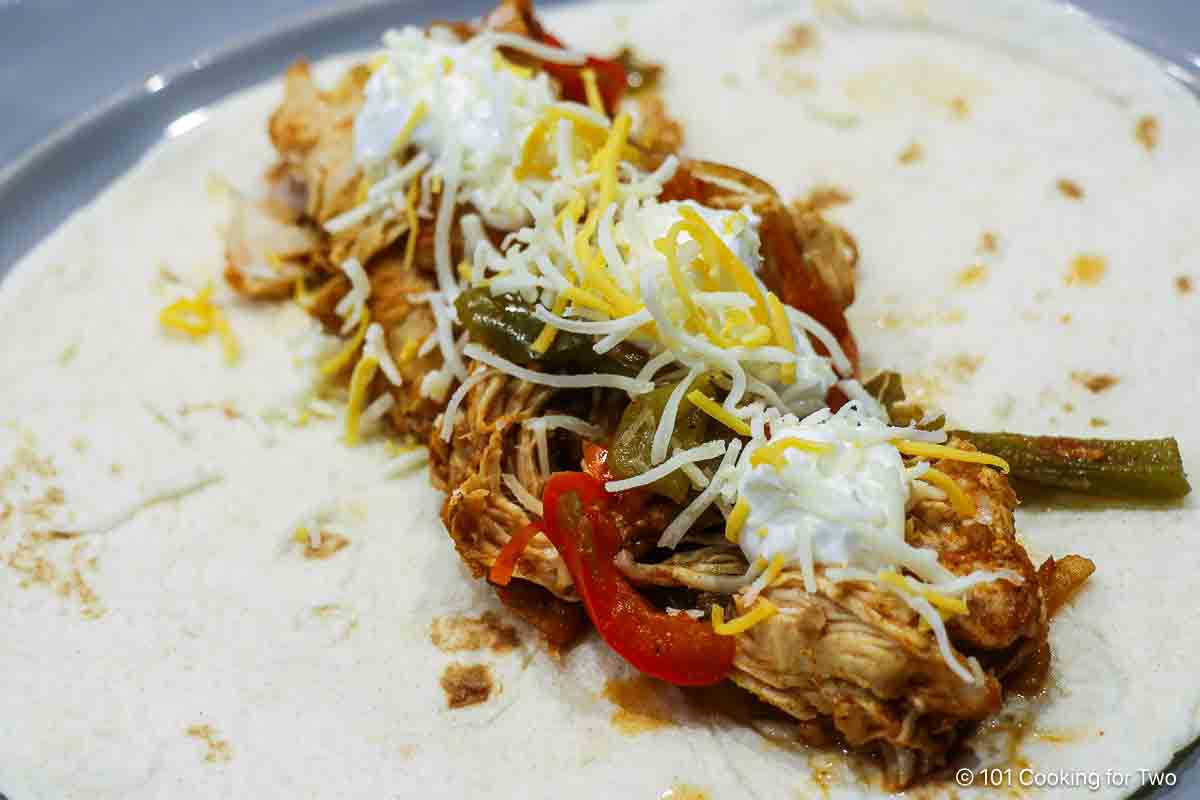 Chicken fajita with toppings on a flour tortilla.