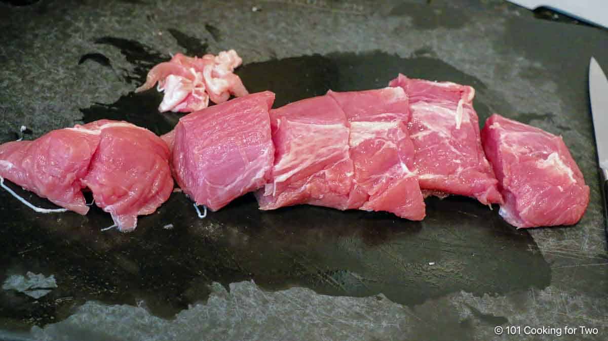 trimmed pork tenderloin on a black board.