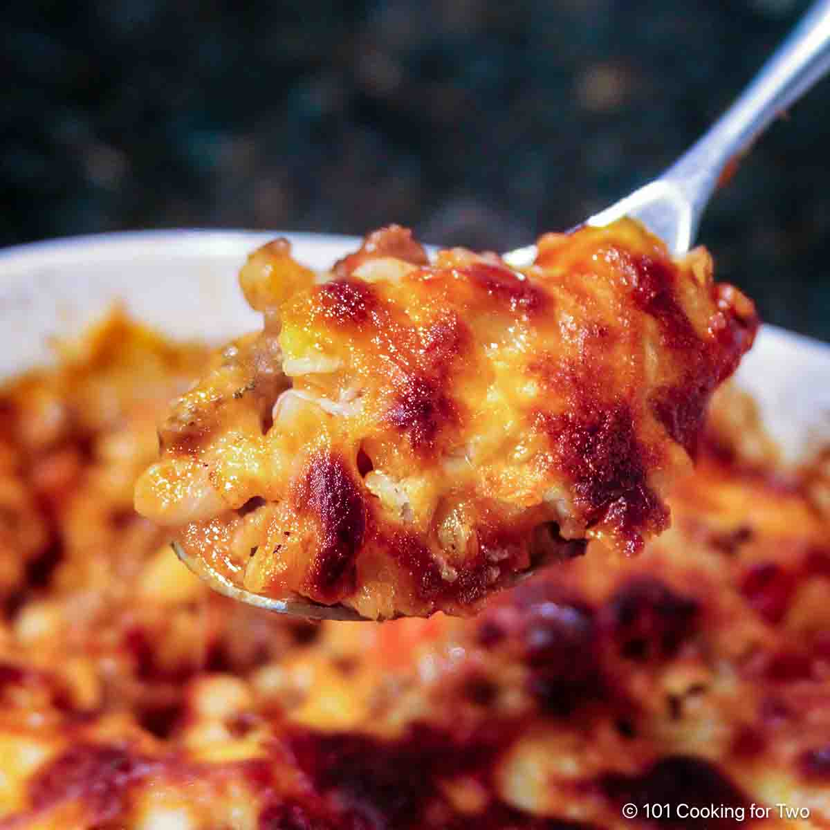 Cheesy goulash on a spoon.