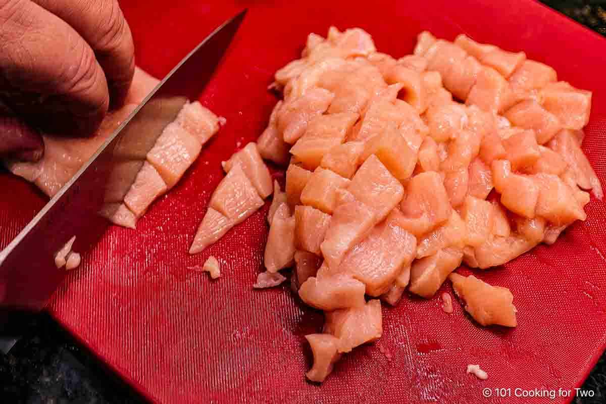 Chopping chicken into small bite-size pieces.