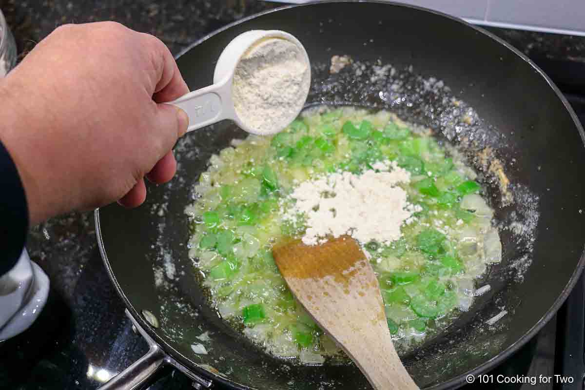 Sprinkling flour into the liquid to make a roux.