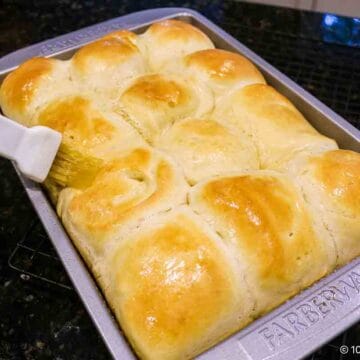 Brushing baked rolls with butter.