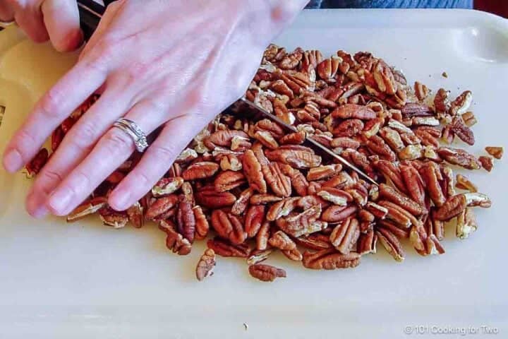 Chopping pecans with a knife.