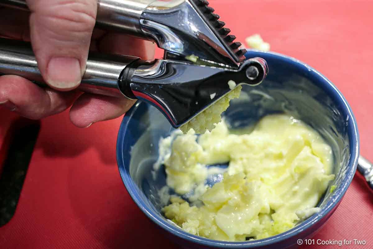 Crushing garlic into butter.