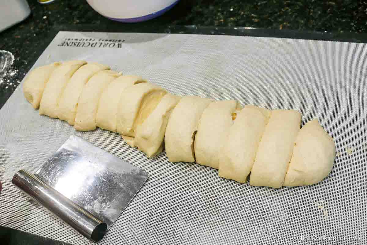 Cutting dough into rolls.