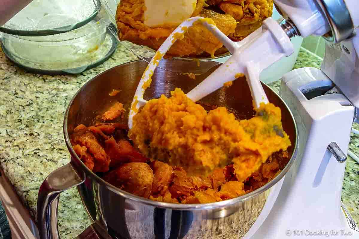 Mashing cooked sweet potatoes in a stand mixer.