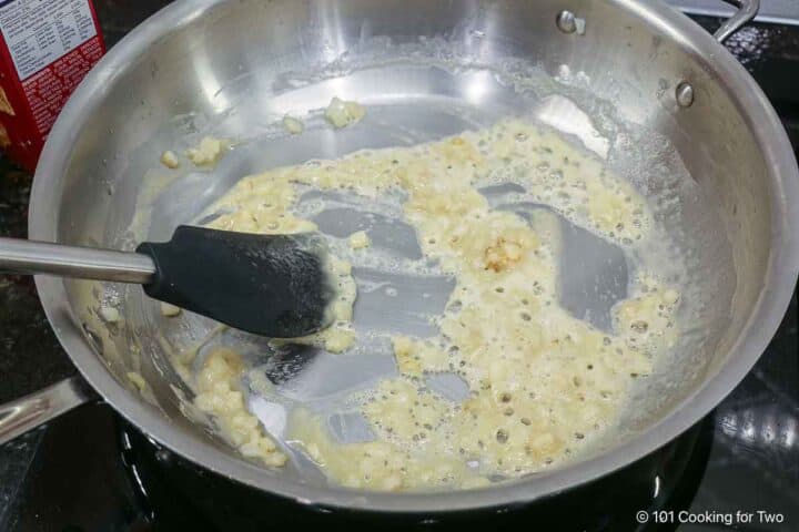 Mixing flour into the butter and onions to make a roux.