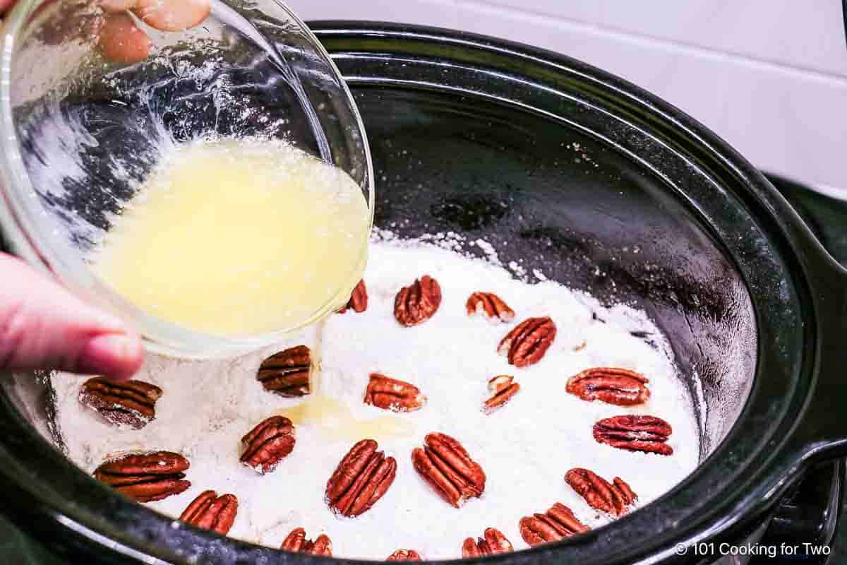 Pouring melted butter over the cobbler.