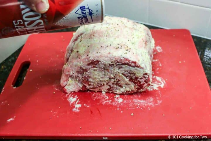 Seasoning a butter covered roast with salt.