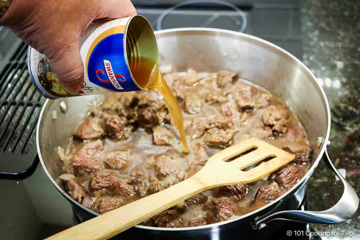 Adding beef broth to browned meat.