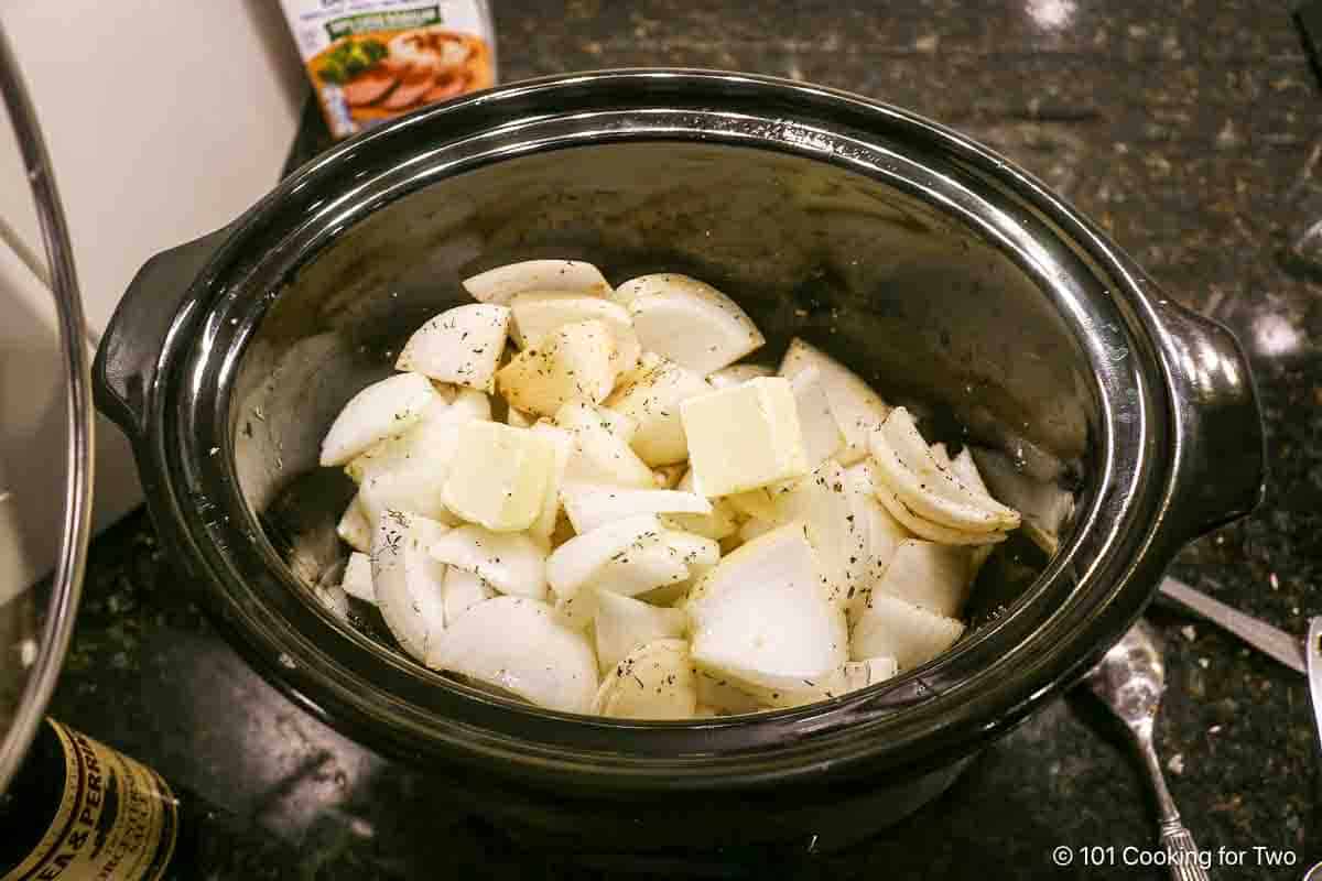 Adding onion and other ingredients to the crock pot.