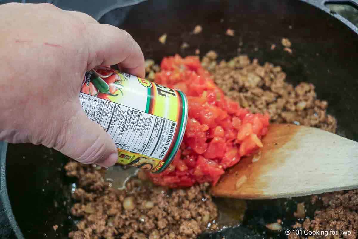 Adding tomato to the sauce.