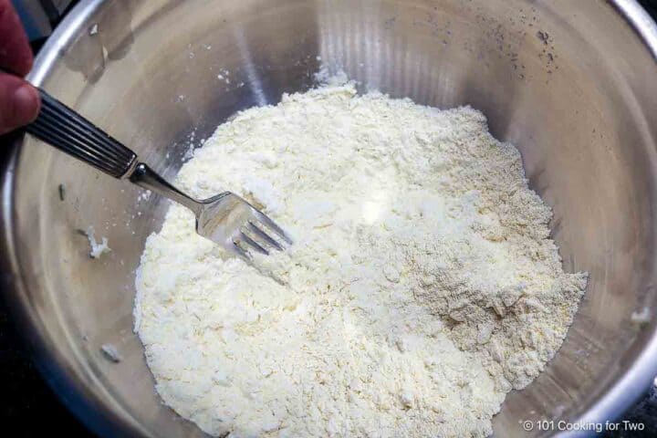 Cutting butter into a dry mixture with cornmeal.