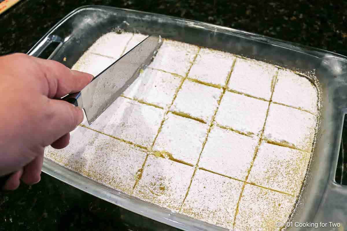 Cutting the baked dish into lemon squares.