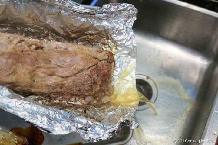 Pouring fluid out to the foil package with cooked ribs.