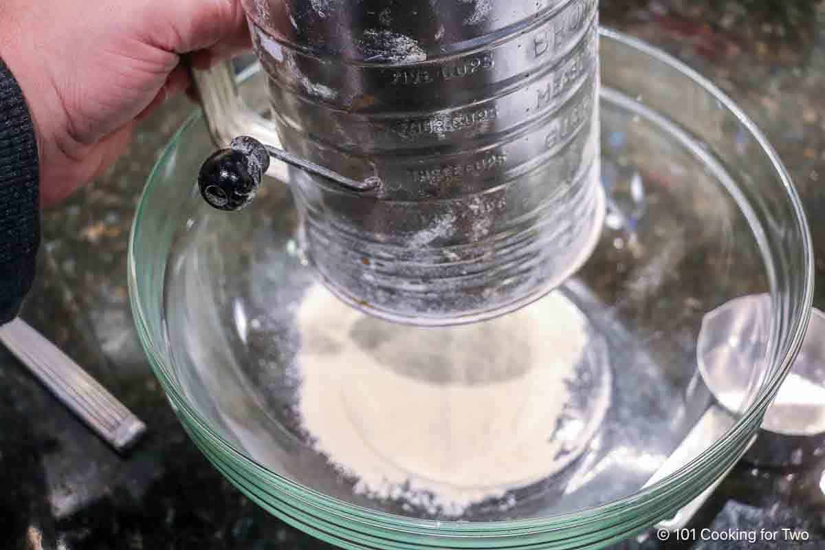 Sifting flour into a clear bowl