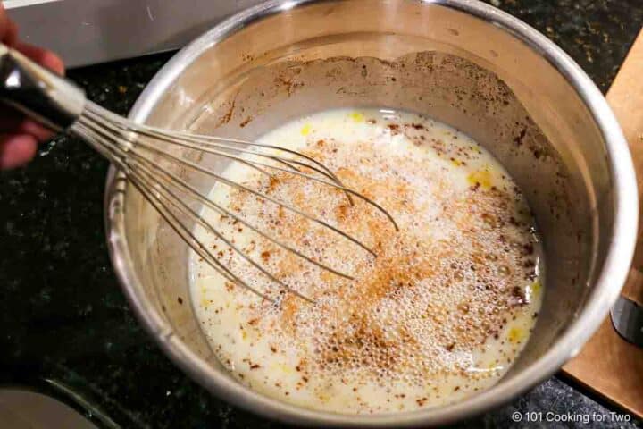 Whisking eggs with milk and seasonings.