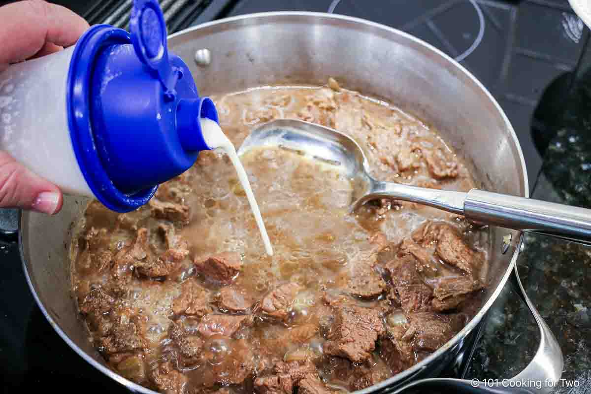 Adding a flour slurry to the simmering beef.