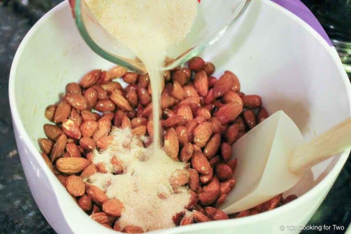 Adding the cinnamon sugar to the coated nuts.