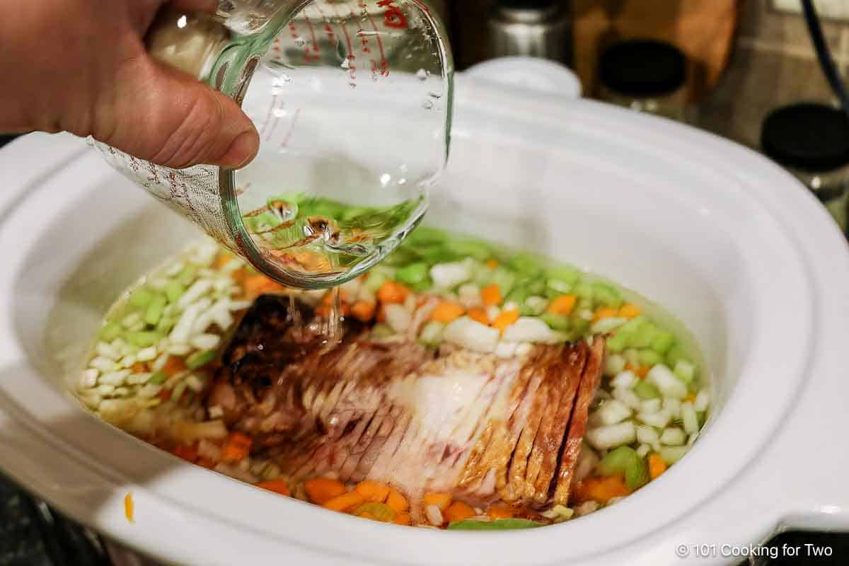 Adding water to the crock pot with ham.