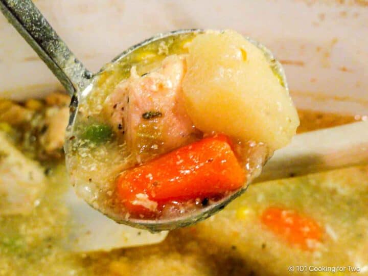 Chicken stew in a ladle over the crock pot.