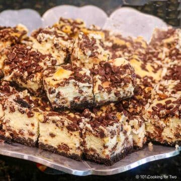 Chocolate chip cheesecake bars on a platter square view.