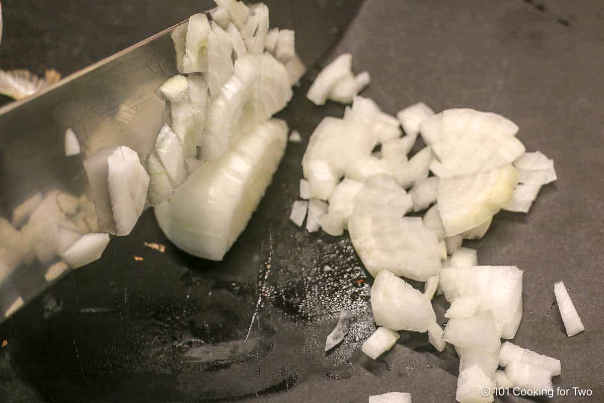 Chopping onion on a black board.