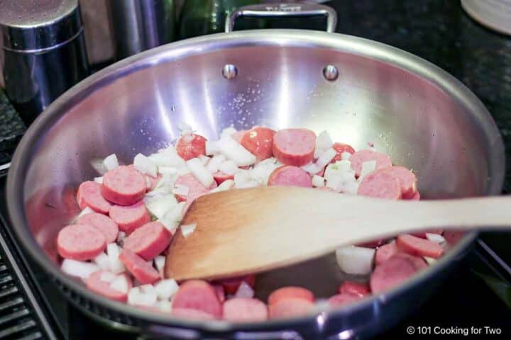 Cooking smoked sausage and onion in a pan.