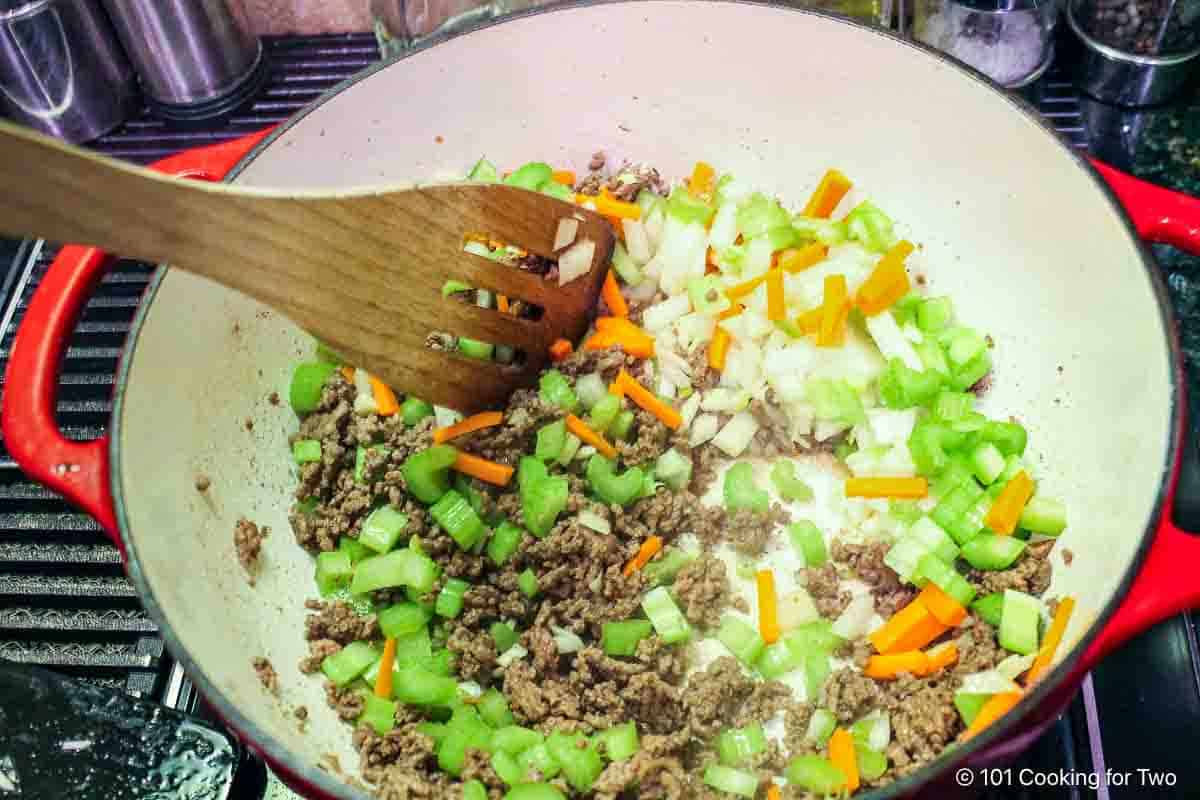 Cooking vegetables with browned meat.