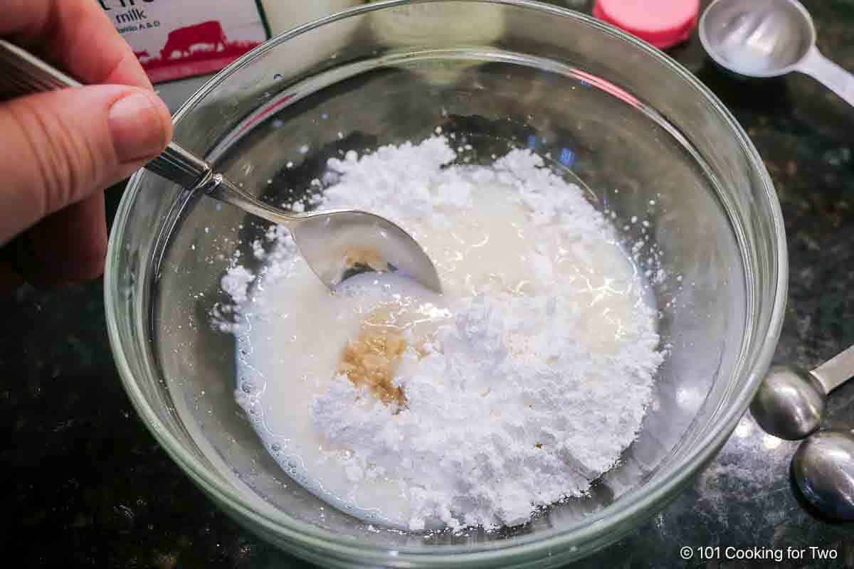 Mixing the glaze of powdered sugar, vanilla and milk.