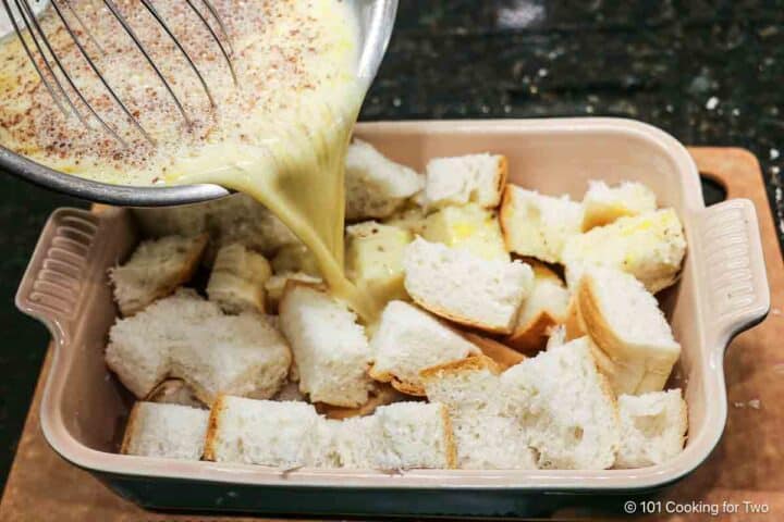 Pouring egg mixture over the bread cubes.