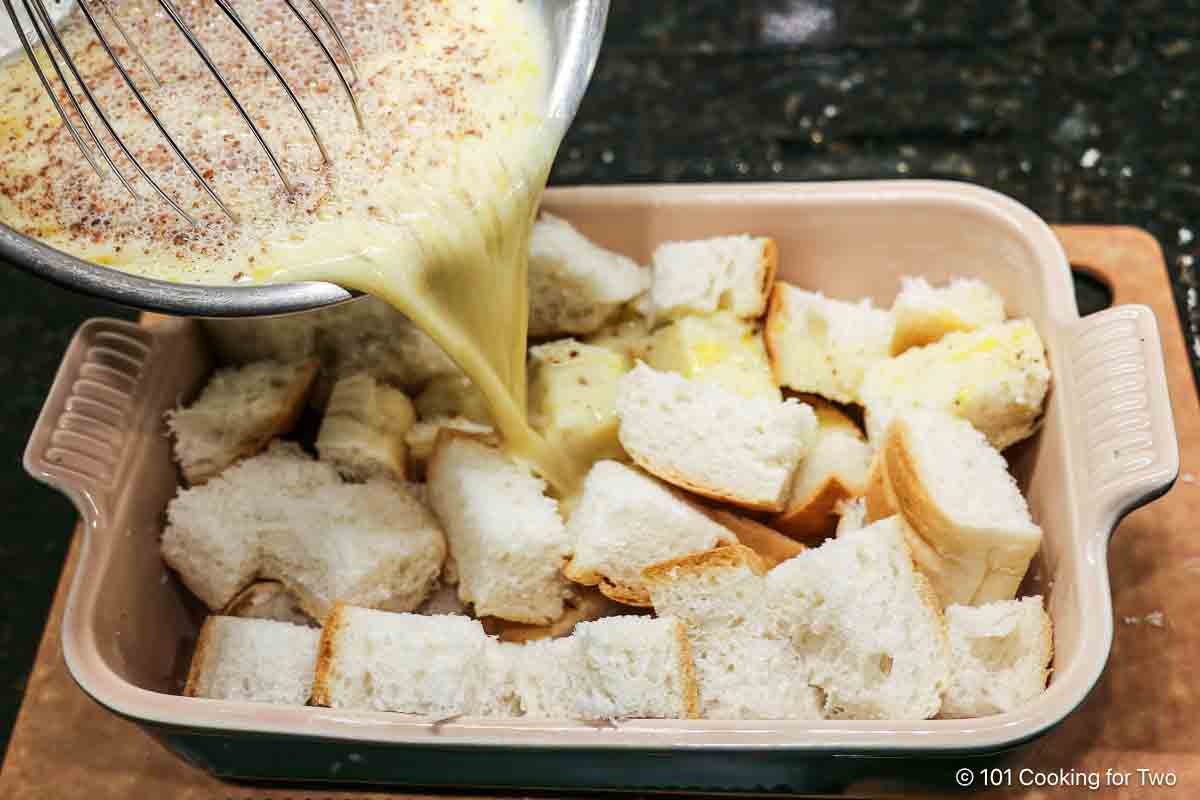 Pouring egg mixture over the bread cubes.