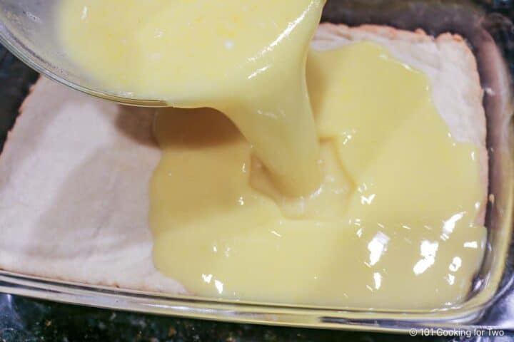 Pouring lemon custard over the baked crust.