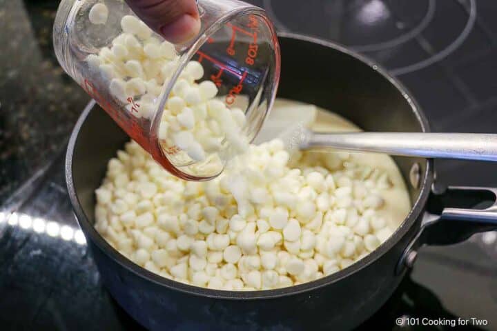 Pouring white chocolate chips into a non-stick sauce pan.