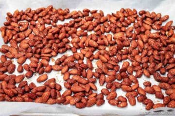 Raw candied almonds on a tray with parchment paper.