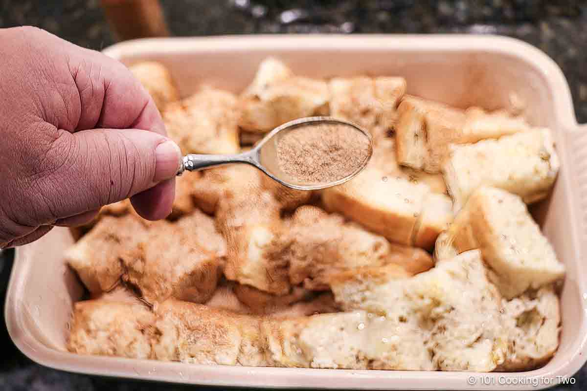 Sprinkling casserole with cinnamon sugar.