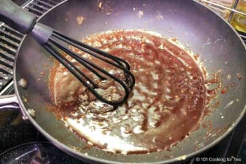 Whisking sauce until thickened.