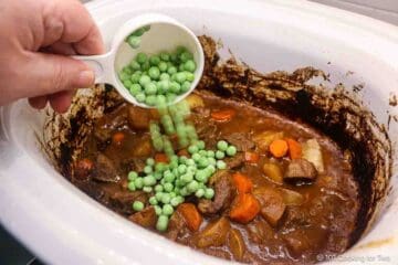 Adding frozen peas to the stew.