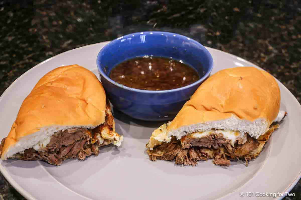 French dip sandwich with au jus in a blue bowl.