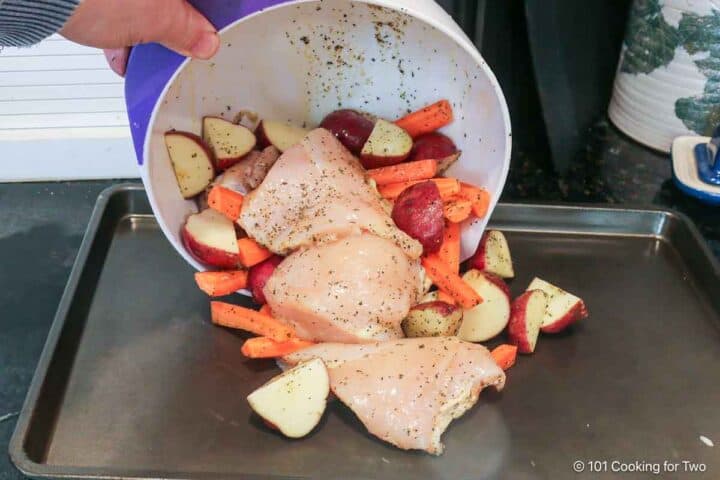 Pouring chicken and veggies onto prepared tray.