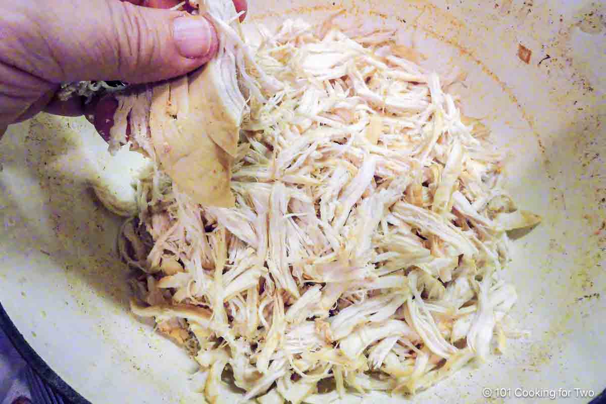 Shredding chicken by hand in the Dutch oven.